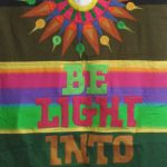 Banner designed by Robert Strobridge with starburst and phrase "Be Light Into Darkness."