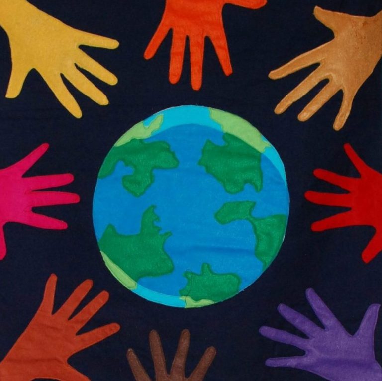 A graphic symbolizing community and connection. A blue and green world graphic with different colored hands surrounding it on a black background.