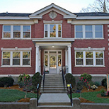 A large red brick building with big windows and front entrance stairs.