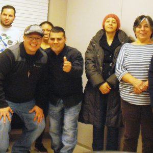 Nine individuals standing together for a group picture indoors.