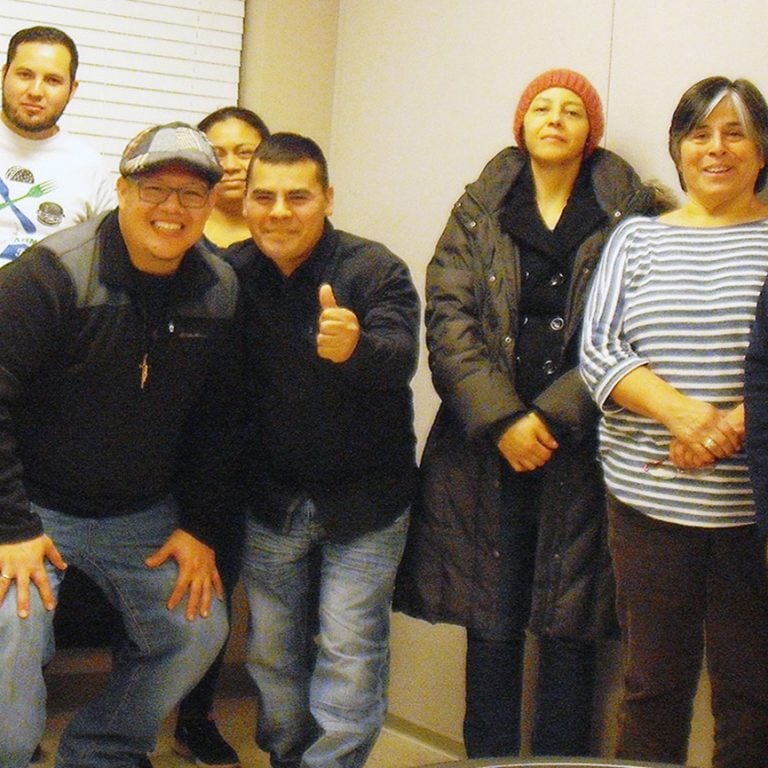 Nine individuals standing together for a group picture indoors.