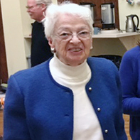 Three women wearing dress clothes smiling together for a group picture indoors.