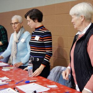 Four women standing at a craft table at a social event pictured candidly.