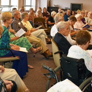 A room full of individuals sitting while attending an event with a speaker not pictured. They are all looking towards the speaker.