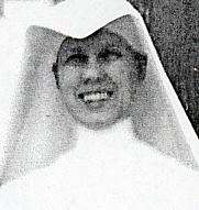 A black and white headshot of a nun brightly smiling for a picture.