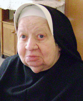 A nun smiles for a picture indoors.
