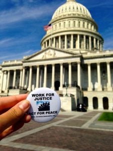 Button with "Work for Justice, Act for Peace" in front of the US capitol.