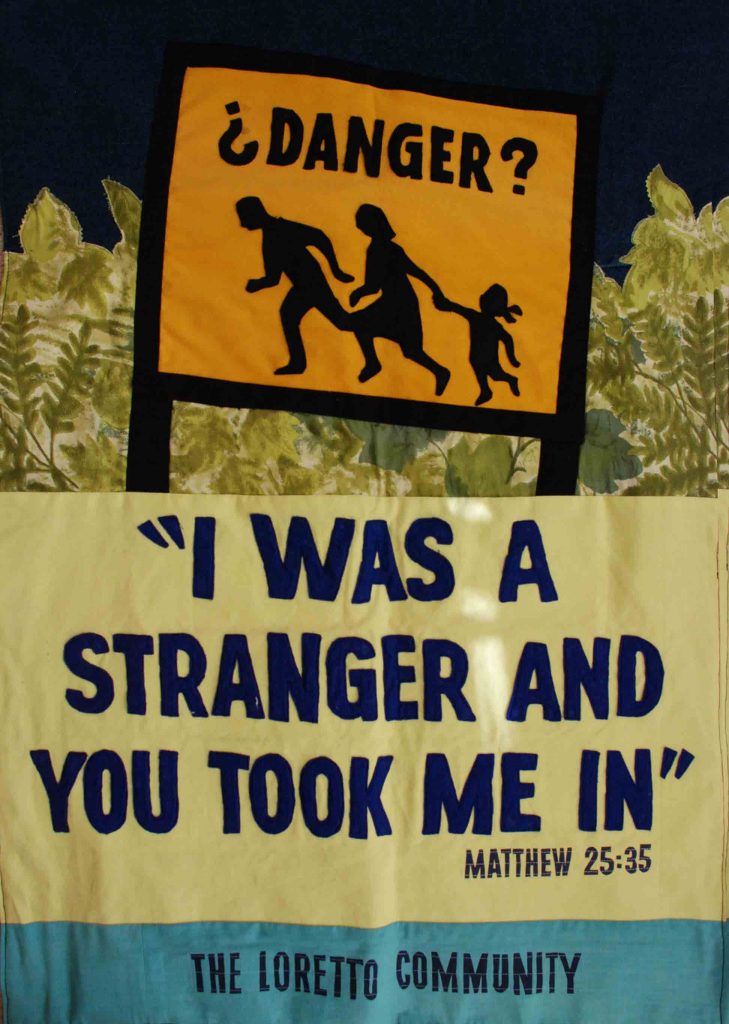 Colorful Loretto Community banner shows a silhouetted family holding hands with the words "Danger?" above. A Gospel quote follows: "I was a stranger and you took me in," Matthew 25:35.