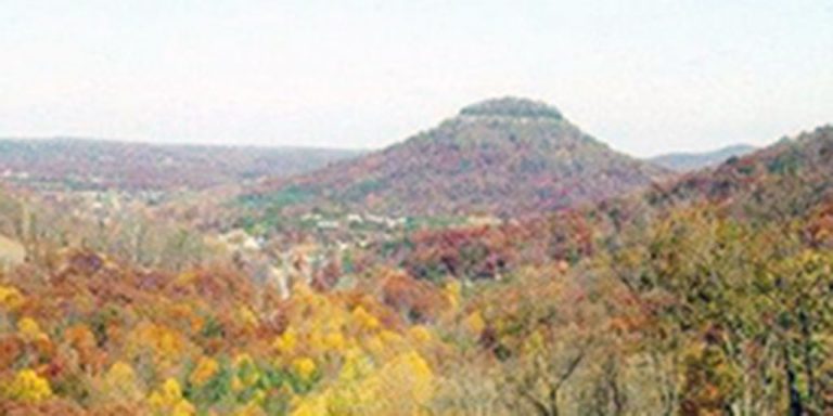 Steep rolling hills covered in multi-colored trees in the fall on a cloudy day.