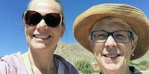 Two women smiling for a selfie picture outdoors on a sunny day.