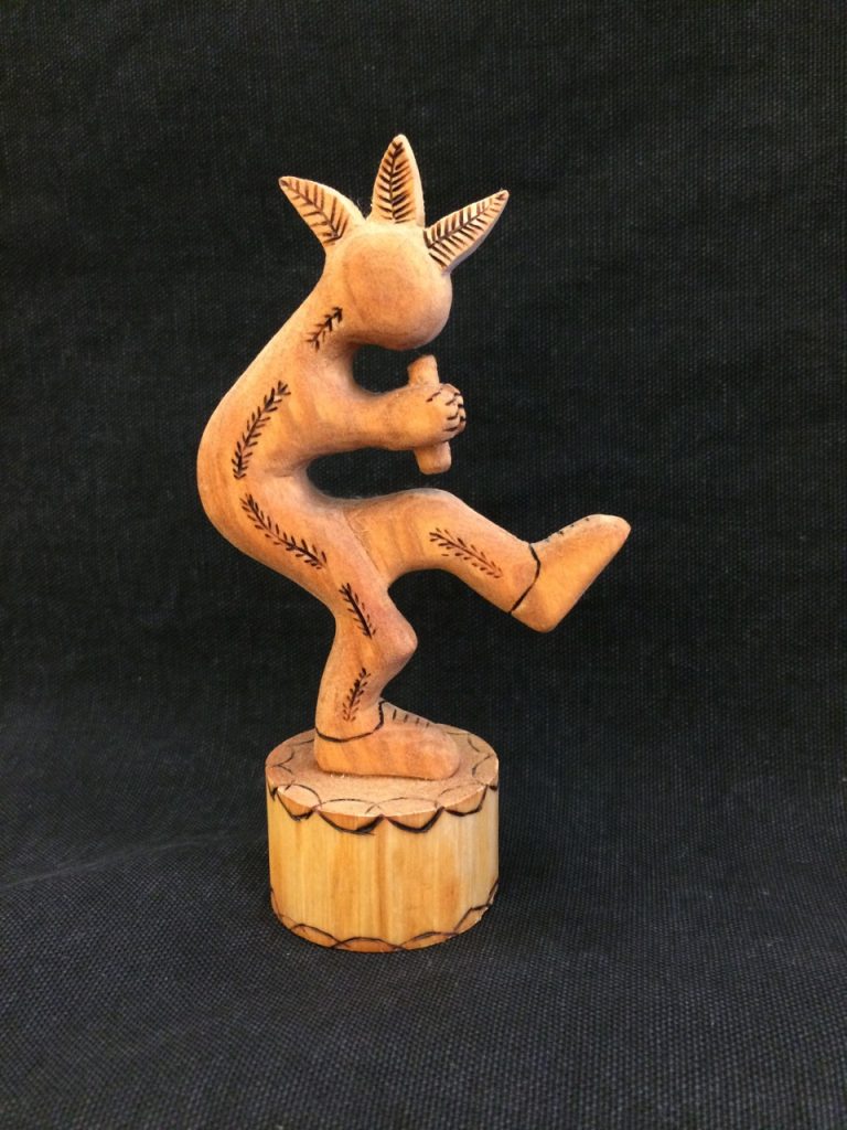 Wooden carving of Kokopelli playing a flute
