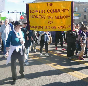 Loretto Community members march with yellow banner in the Denver Marade