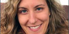 A woman with light brown hair and blue eyes smiling for a headshot picture.