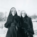 Photo of two sisters standing out in the snow in winter habits