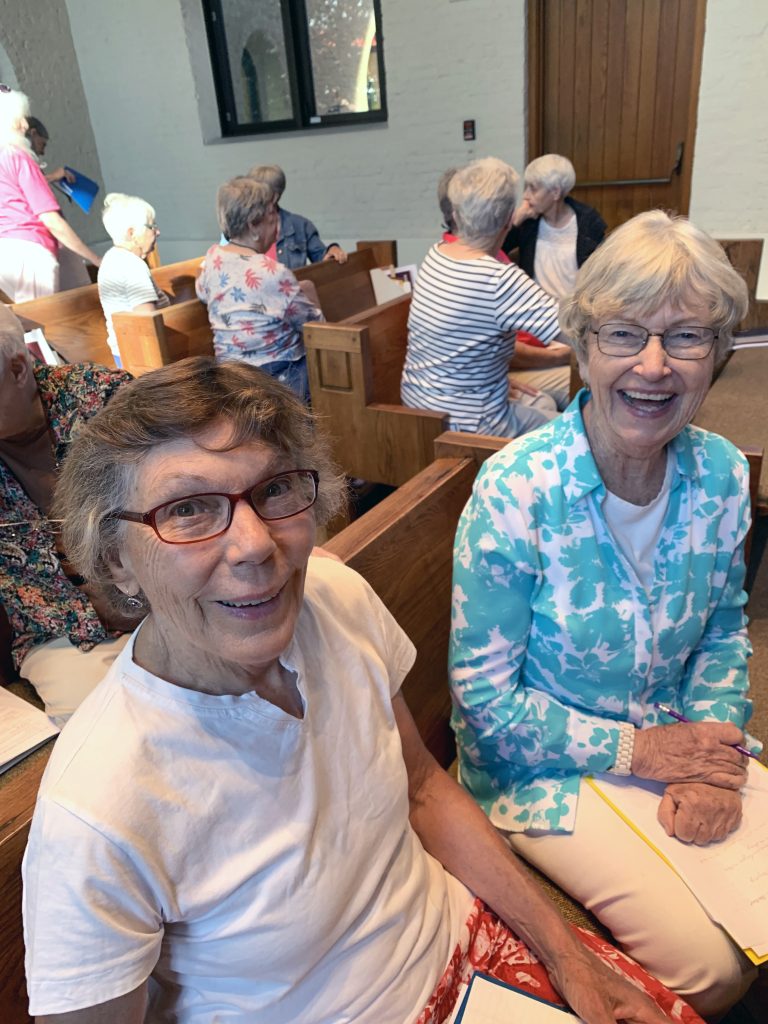Two women sitting in a chapel smiling at the camera