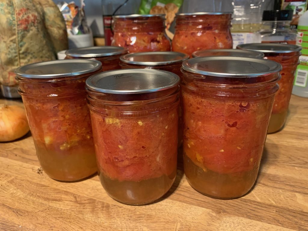 Jars of canned tomatoes are displayed on a countertop.