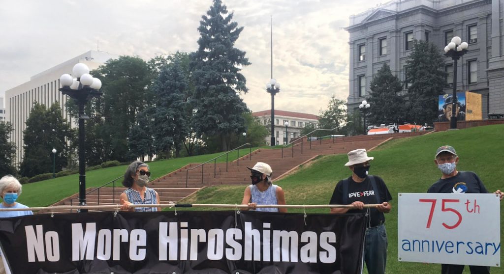 Masked Loretto Community members stand with a sign reading "No More Hiroshimas" outside the Colorado capitol building in Denver in August.