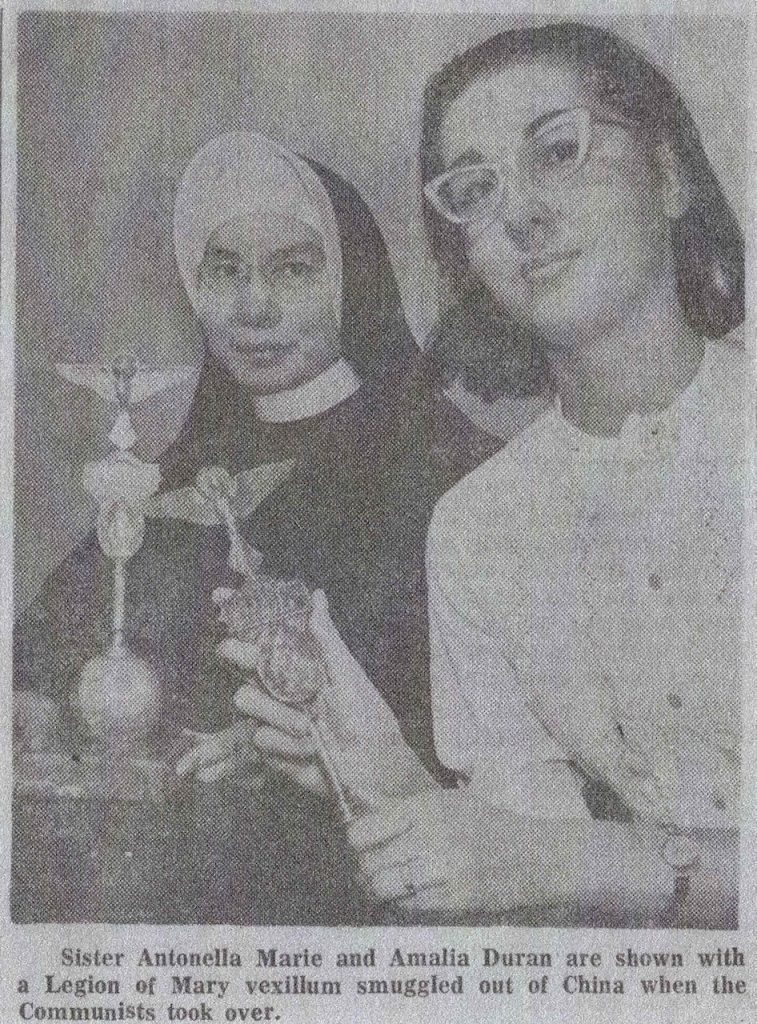 A historical newspaper photo of a nun in habit and a woman in glasses each holding the same standard.