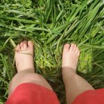 Child's bare feet in long green grass.