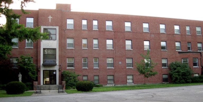 Long, four story brick building with a cross above the entrance.