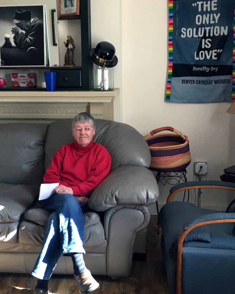 Woman in red turtleneck sits on a couch in sun splashes