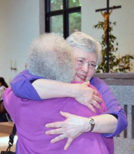 Two women embrace.