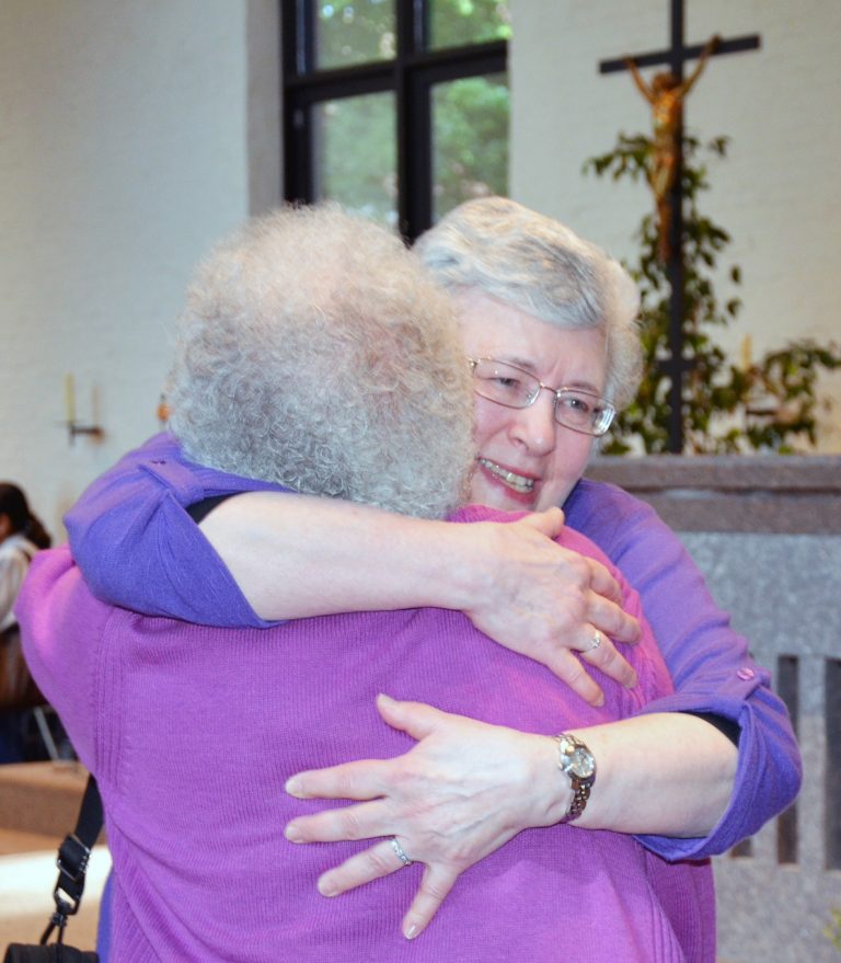 Two women embrace.