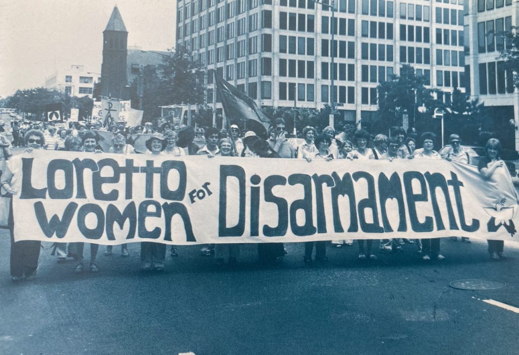 Archival photo of Loretto members in a march. The banner they carry reads "Loretto Women for Disarmament"