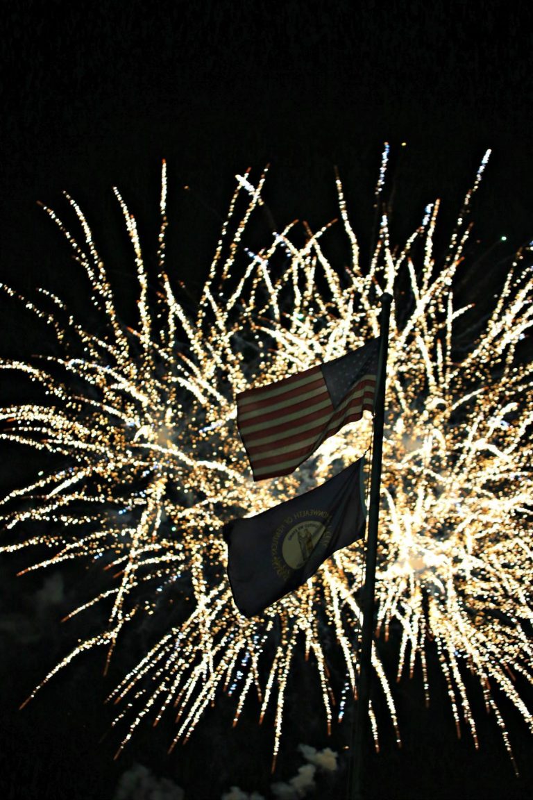 Fireworks backlight the American and Kentucky flags