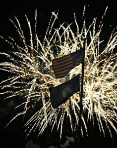 Fireworks backlight the American and Kentucky flags