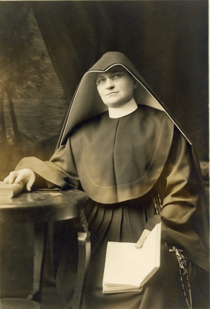 A habited nun sits with an open book in this archival photo