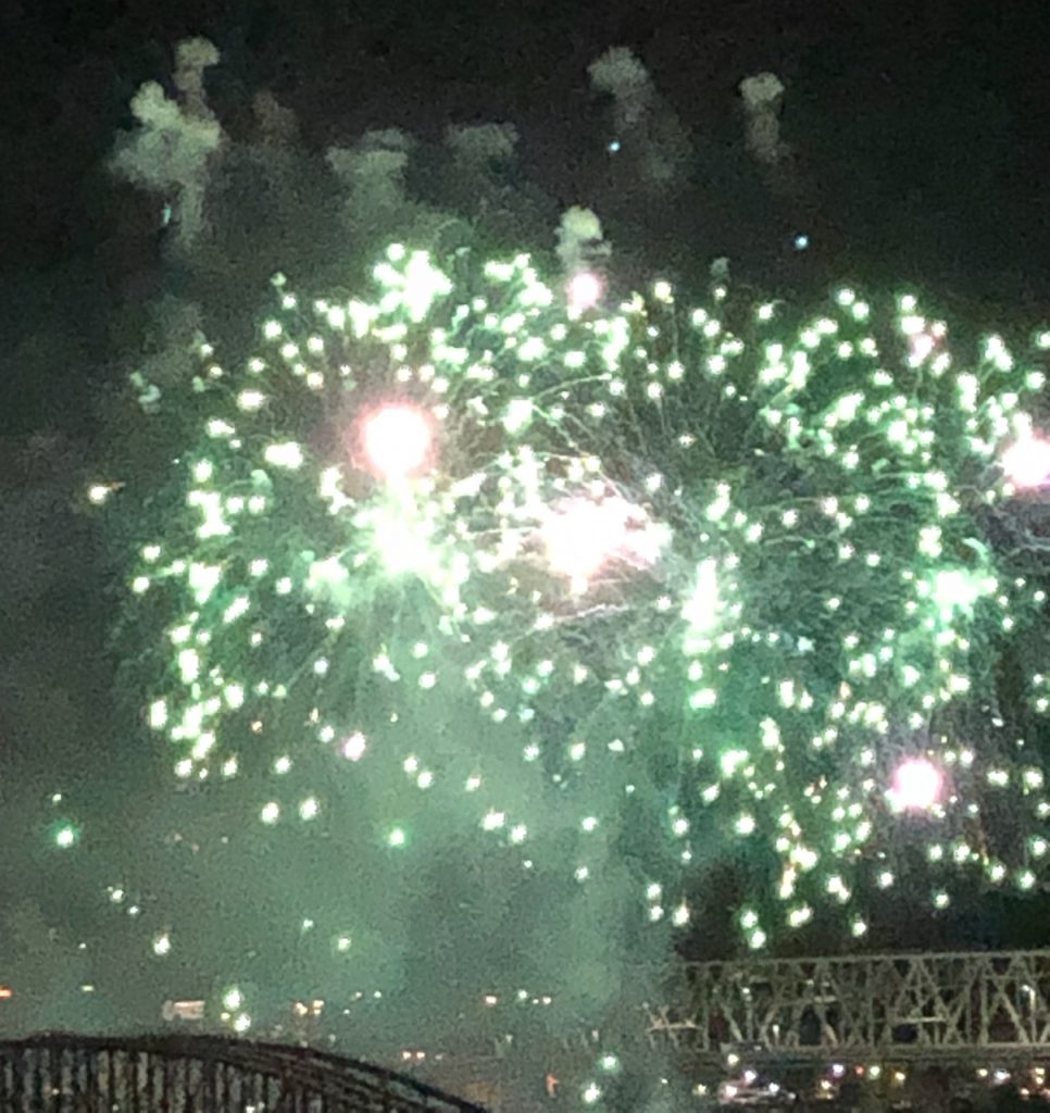 Green fireworks sparkle over a bridge