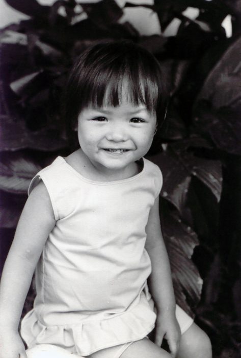 A Vietnamese toddler girl smiles for the camera.