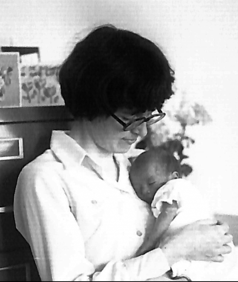 A woman cradles a dozing infant in this archival photo.