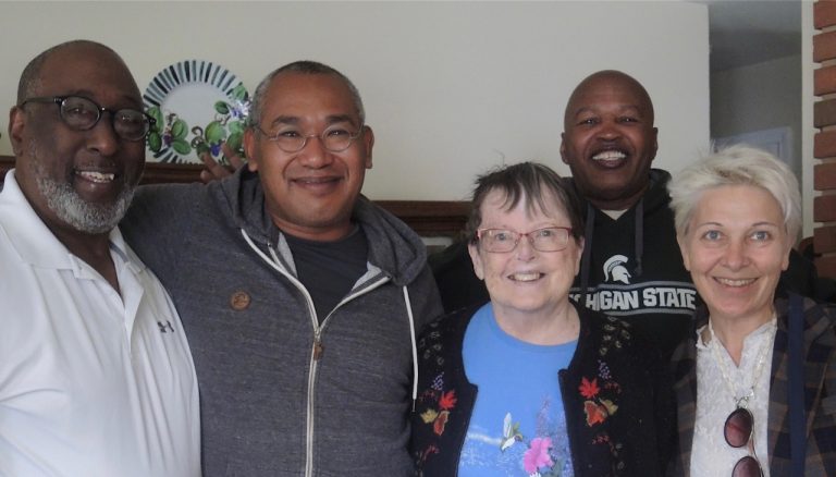 Three men and two women stand together, smiling, for the photographer.