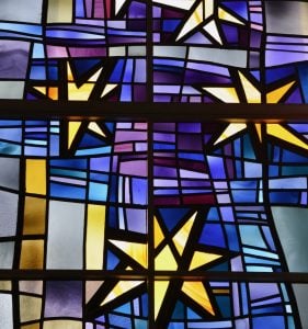 A stained glass window shines with golden stars and a blue and purple background