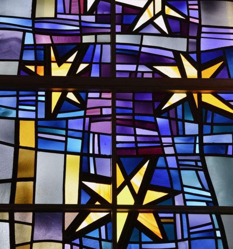 A stained glass window shines with golden stars and a blue and purple background