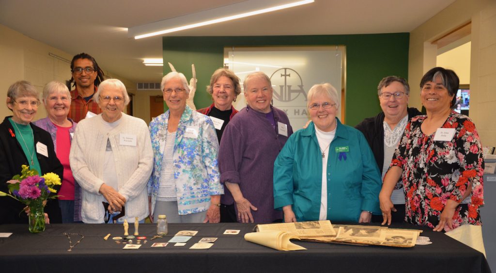 Loretto Community members stand for a photo behind a table of items for the time capsule.