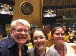 Three women smile for a selfie inside the UN