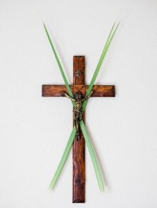 Woden crucifix with two palms crossed behind Christ