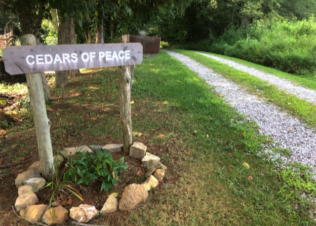 A carved wooden road sign reads "Cedars of Peace"