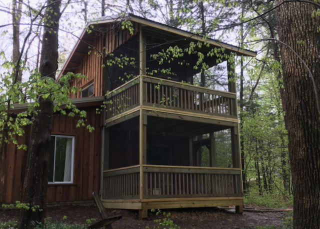 A two-story wooden cabin includes stacked porches.