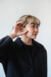 a woman in black long sleeves with her hand on ear