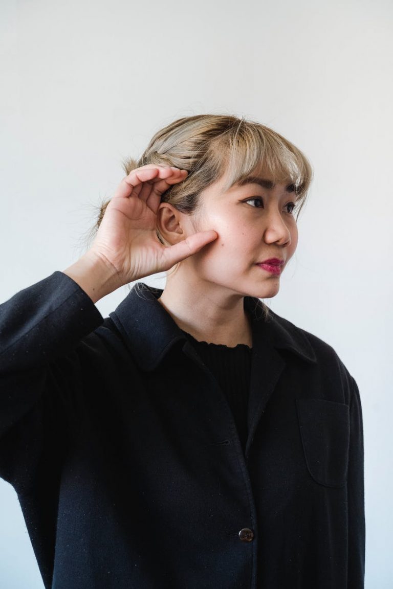 a woman in black long sleeves with her hand on ear