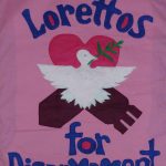 A pink banner with a white dove in the middle has blue lettering around it saying "Lorettos for Disarmament"