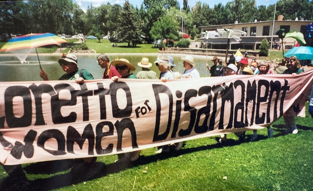 People carry a large banner reading "Loretto Women for Disarmament" in a protest march on the grass.