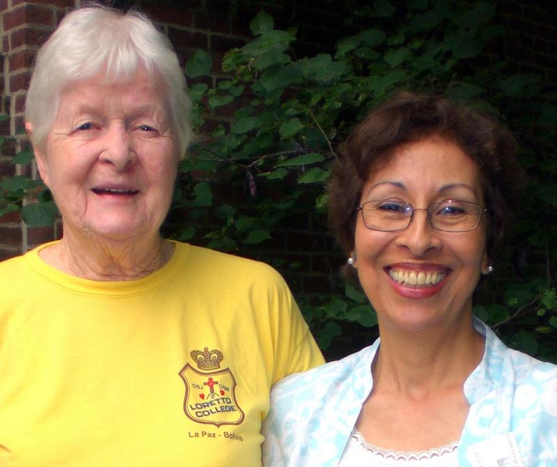 Photo of two women smiling together. The older woman on the left wears a yellow shirt with the "Loretto College" patch logo