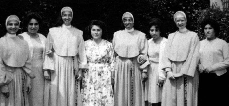 Archival photo of habited nuns posed in a line with staff women.