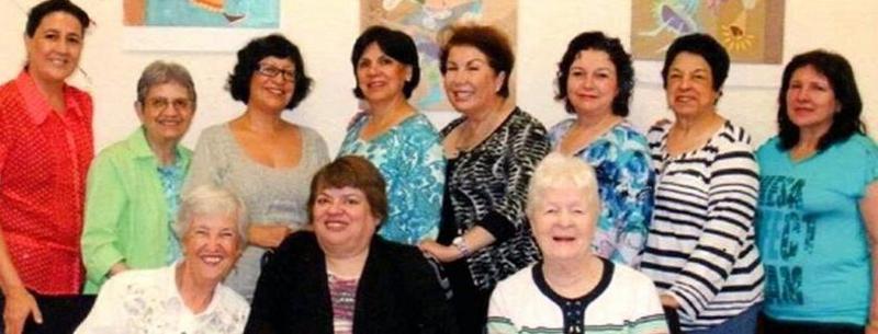 Women at their 40th class reunion pose for a photo with their former teachers.