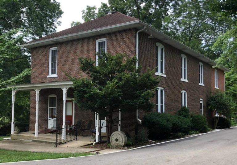 Two story brick building with white trim around the front posts, door and window frames.